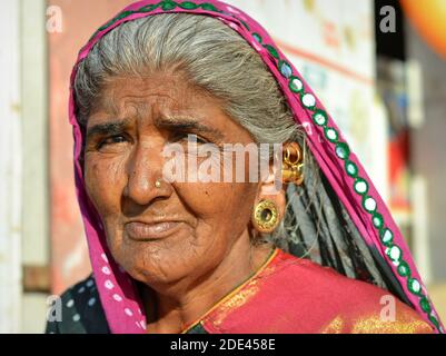 Vieille femme indienne Gujarati avec des bijoux d'oreille élaborés (bouchons de lobe d'oreille, piercings d'hélice d'oreille) et le foulard traditionnel de tête (dupatta) pose pour l'appareil photo. Banque D'Images