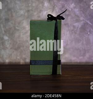Boîte de parfum verte avec un ruban noir sur une obscurité table en bois Banque D'Images