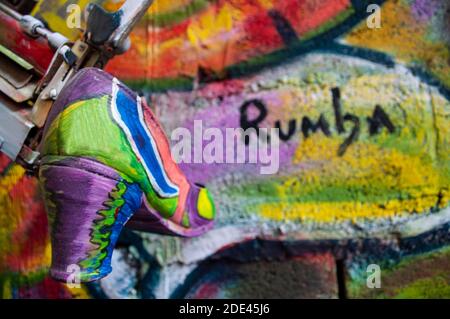 Chaussures de danse flamenco peintes en différentes couleurs, accrochées d'une vieille machine à écrire sur un mur de plusieurs couleurs et avec le mot rumba écrit sur lui, moderne A. Banque D'Images