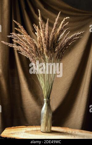 bouquet de fleurs sauvages dans un vase en verre sur fond marron Banque D'Images