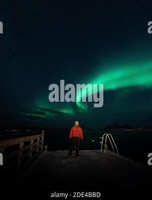 Le nord illumine un fjord norvégien avec une personne en blouson rouge, Tromso, Norvège Banque D'Images