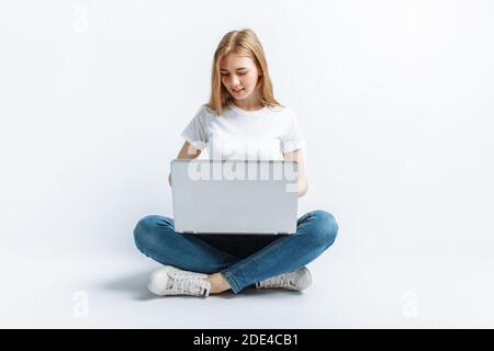 Belle fille assise et dactylographiant sur ordinateur portable, shopping, dans Studio Banque D'Images