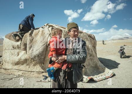 Homme portant l'enfant dans ses bras, kirghize nomade, derrière lui yourte traditionnel, qui est démantelé, plateau de Bozai Gumbaz, couloir de Wakhan Banque D'Images