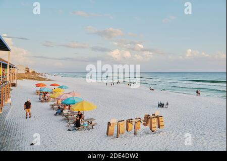 Les gens se détendent sur la plage de sable blanc au coucher du soleil à côté d'un bar de plage au restaurant Pompano Joe's à destin, Floride, États-Unis. Banque D'Images