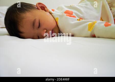 Le petit garçon dormait sur le lit, dormant en position ventrale. Banque D'Images