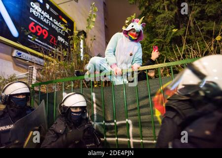 Un manifestant habillé comme une licorne saute sur une clôture à une propriété privée alors qu'ils s'échappent de la police anti-émeute pendant la manifestation. Une autre journée de protestation organisée par le Strajk Kobiet (grève des femmes) après le jugement du Tribunal constitutionnel, qui a resserré la loi sur l'avortement en Pologne, a eu lieu dans le cadre de la célébration du 102e anniversaire de l'obtention des droits électoraux par les femmes polonaises. "Varsovie indépendante - au nom de mère, fille, sœur" - sous ce slogan, des milliers de manifestants ont défilé dans les rues de Varsovie, causant des difficultés de circulation importantes. Banque D'Images