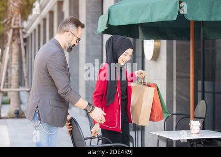 Bonne femme musulmane et garçon freind avec la main de shopping de ville sacs en papier Banque D'Images