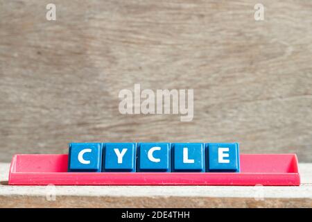 Lettre de carreau sur le portoir rouge dans cycle de mot sur bois arrière-plan Banque D'Images