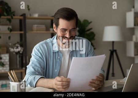 Un jeune homme souriant a lu de bonnes nouvelles dans la lettre postale Banque D'Images