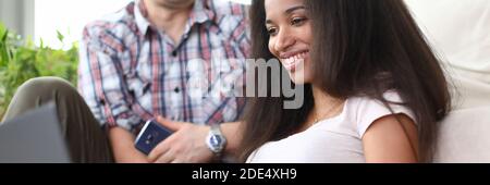 Une fille souriante assise sur le sol avec un ordinateur portable près d'un gars Banque D'Images