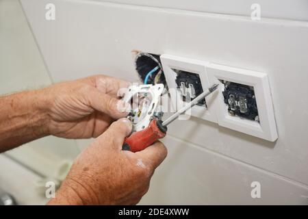 Un électricien est en train de réparer et d'installer une prise, un bouchon de sortie. Banque D'Images