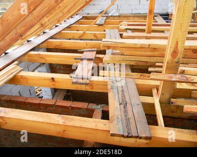 Construction inachevée de toiture de maison de grenier avec des fermes, poutres en bois, éfs, bois. Construction de cadre en bois de toit de maison. Banque D'Images