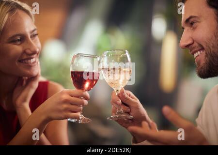 beau jeune couple caucasien en train de déguster du vin au dîner, en regardant les uns les autres, souriant. Banque D'Images