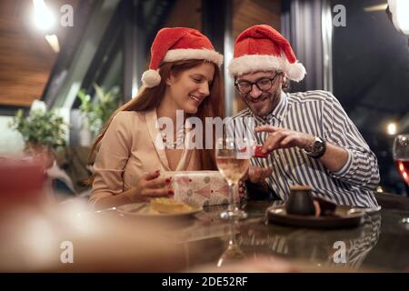 jeune couple caucasien échange de cadeaux avec santa chapeaux. christmastime, Banque D'Images