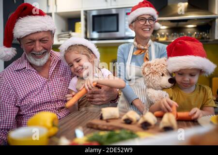 Joyeux grand-parent appréciant avec des petits-enfants dans la préparation de repas de Noël dans une atmosphère festive dans la cuisine. Noël, famille, ensemble Banque D'Images