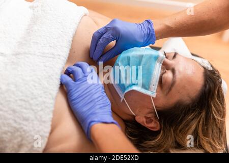 physiothérapeute donnant le traitement avec l'acupuncture à aiguille sèche à la patiente dans la poitrine, elle utilise un masque de protection coronavirus Banque D'Images