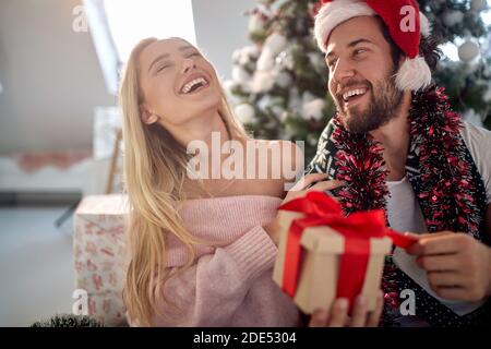joyeux jeune couple caucasien s'amuser tout en ouvrant des cadeaux de noël, rire Banque D'Images
