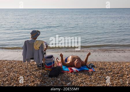 Angleterre, West Sussex, Worthing, Worthing Beach, couple de personnes âgées bains de soleil sur la plage Banque D'Images