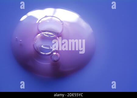 Gel de sérum crème floue texture d'échantillon cosmétique transparente avec bulles isolées sur fond bleu. Texture de gel liquide. Mise au point sélective, DEP. Peu profonde Banque D'Images