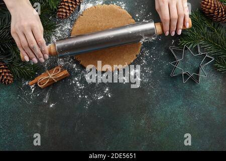 Femme qui fait des biscuits de pain d'épice avec un rouleau. Préparation des fêtes de Noël. Banque D'Images