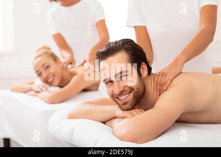 Couple joyeux recevant un massage du cou au spa Banque D'Images