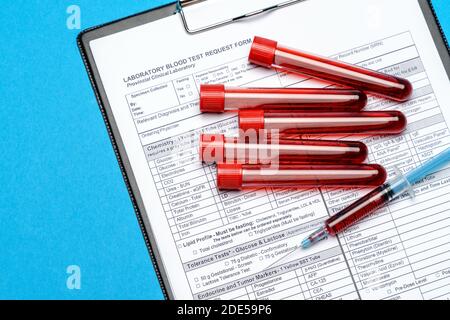 Presse-papiers avec papier vierge avec tubes à essai sur le sang arrière-plan bleu Banque D'Images