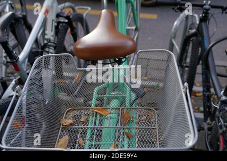 Vélo avec panier métallique avec quelques feuilles sèches. Un détail d'un parking pour vélos dans le centre-ville de Lucerne, Suisse. Banque D'Images