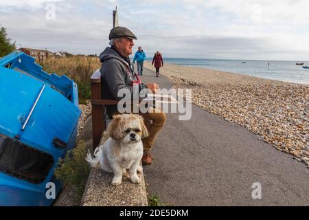 Angleterre, West Sussex, Chichester, Selsey Bill, homme âgé assis avec chien sur le front de mer Banque D'Images