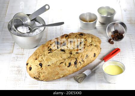 Stollen traditionnel de Noël Saxon fraîchement cuit avec quelques ingrédients de boulangerie à terminer avec du sucre en poudre Banque D'Images