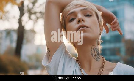 Portrait d'une belle jeune femme blonde aux cheveux courts dans le parc pendant le coucher du soleil. Photo de haute qualité Banque D'Images