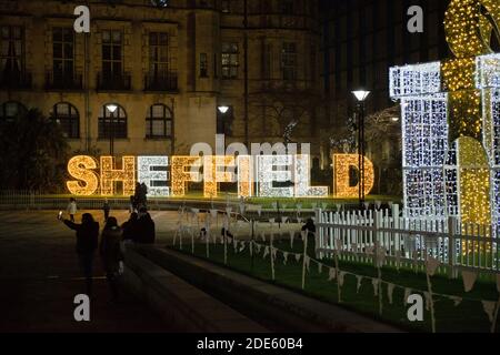 Sheffield, Royaume-Uni, 27 novembre 2020 : lumière de noël en centre-ville dans les jardins de la paix. Personnes prenant des photos avec le cadeau éclairé Banque D'Images