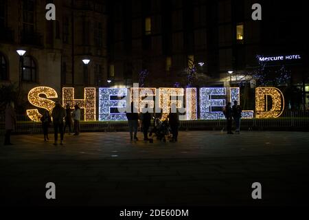 Sheffield, Royaume-Uni, 27 novembre 2020 : gros plan de Sheffield illuminé de lumières de noël. Des groupes de personnes se tiennent devant. Banque D'Images