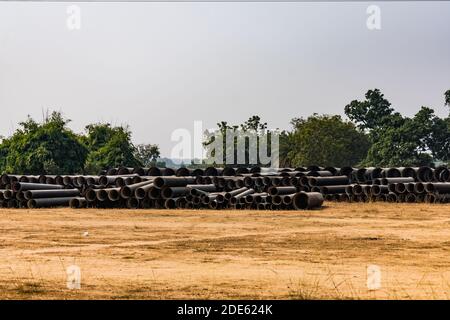 tuyaux en fonte ductile stockés dans l'espace ouvert d'une cour de magasin de village rural. Banque D'Images