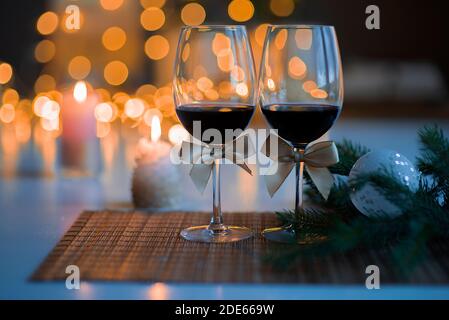 Ambiance de Noël festive avec deux verres de vin et un bougie allumée sur la table de cuisine Banque D'Images