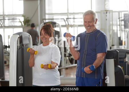 Couple senior heureux de lever des haltères à la salle de gym. Banque D'Images