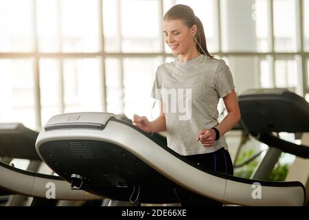 Jeune femme faisant de l'exercice cardio sur le tapis roulant dans la salle de gym. Banque D'Images