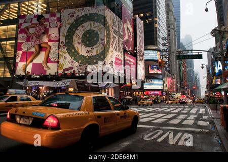 Des taxis jaunes dans Times Square la nuit devant la grande Liberty of London lancent des panneaux publicitaires, New York, États-Unis Banque D'Images