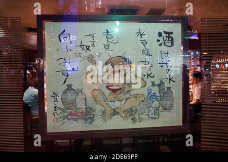 Les personnes dînant à l'intérieur d'un restaurant japonais avec un panneau de rideau de démon de sourire à Tokyo, au Japon Banque D'Images