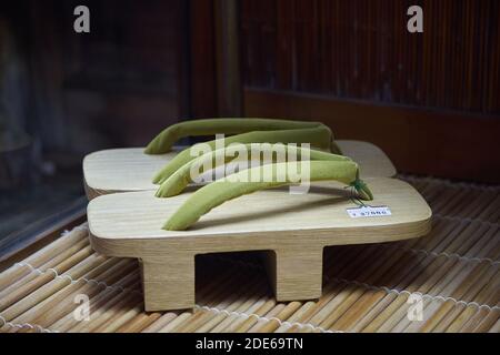 Une paire de geta avec un matériau supérieur vert lime dans un présentoir de vitrine de magasin, Japon Banque D'Images