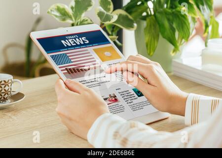 Photo d'une femme lisant des nouvelles dans un journal en ligne avec sa tablette dans le salon. Tout le contenu est composé Banque D'Images