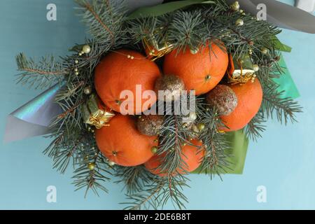 Bouquet de Noël de branches de sapin, mandarines et petites boîtes-cadeaux sur fond bleu. Nouvelle année Banque D'Images