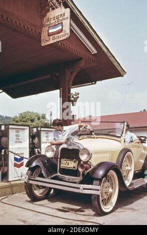 Warren Brown, propriétaire de la station-service et de l'épicerie sur main Street à Helen, en Géorgie, est assis dans une Ford 1929 tandis que son fils fait l'essence de la voiture; un des nombreux qu'il a ramassé au fil des ans Banque D'Images