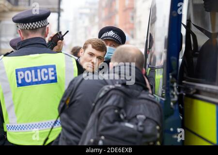 Londres, Royaume-Uni. - 28 novembre 2020 : un homme est détenu lors d'une manifestation anti-verrouillage dans la capitale alors qu'un photographe prend une image. Banque D'Images