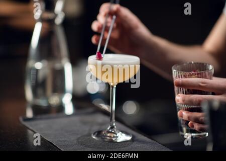 Gros plan d'un verre avec un délicieux cocktail sur la table dans un restaurant. Le barman crée une boisson alcoolisée pour les femmes. Banque D'Images