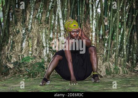 Femme africaine assise en face de la forêt de bambou avec l'Africain Peinture de visage à Aburi Ghana Afrique de l'Ouest Banque D'Images