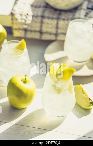 Cocktail d'été avec pomme verte et glace sur la table blanche près de la fenêtre en été ensoleillé. Image à mise au point sélective avec espace de copie Banque D'Images