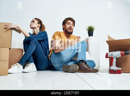 homme et femme assis sur le sol avec leur dos à d'autres travaux de rénovation déplacer une fleur dans un pot Banque D'Images