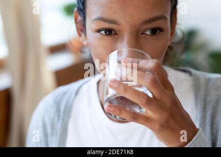 Gros plan de la femme biraciale boire de l'eau minérale Banque D'Images