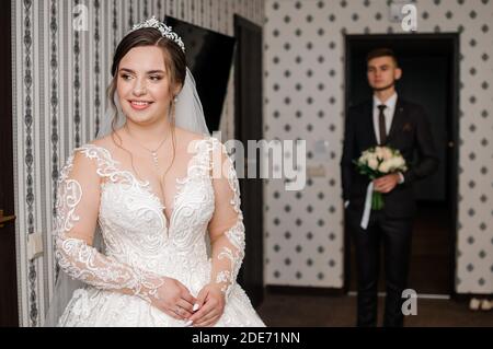 le marié rencontre la mariée et donne un bouquet de fleurs dans la chambre d'hôtel Banque D'Images