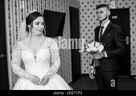 le marié rencontre la mariée et donne un bouquet de fleurs dans la chambre d'hôtel Banque D'Images